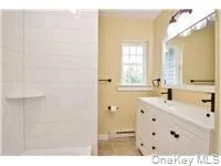 a bathroom with a sink vanity granite tub shower and a mirror