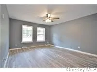 a view of an empty room with window and wooden floor