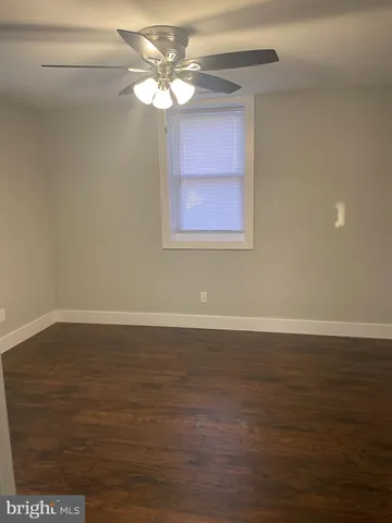 a view of a livingroom with an empty space a ceiling fan and wooden floor