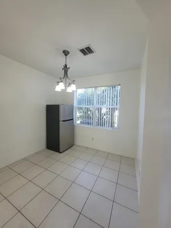 an empty room with windows and chandelier fan