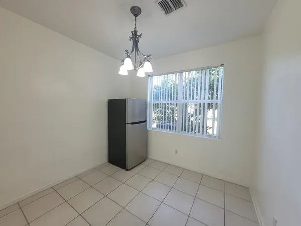 an empty room with a chandelier fan and windows