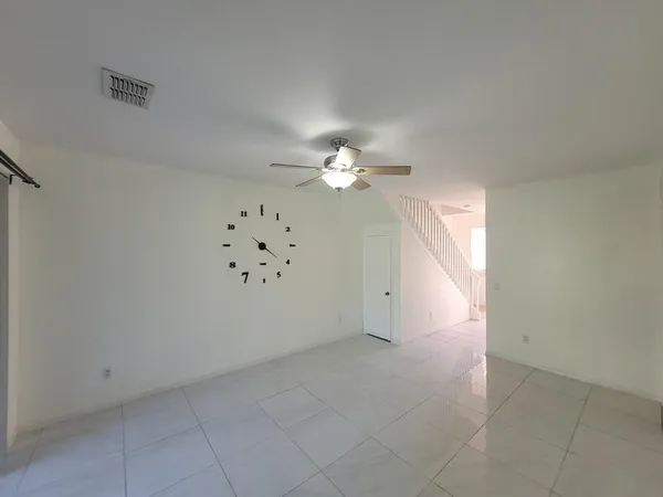 an empty room with chandelier fan and windows