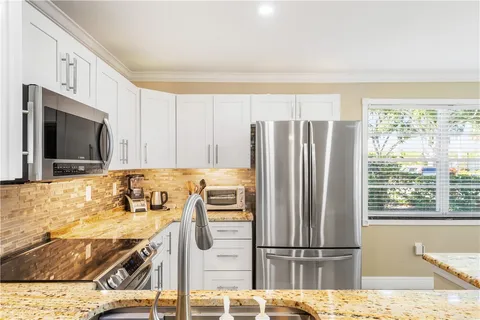 a kitchen with stainless steel appliances granite countertop a refrigerator a stove and a sink with granite countertops