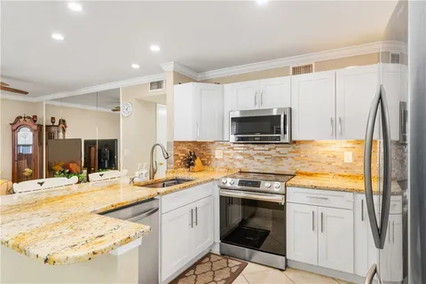 a kitchen with stainless steel appliances kitchen island granite countertop a sink stove and refrigerator