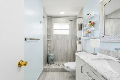 a bathroom with a granite countertop sink a toilet and shower