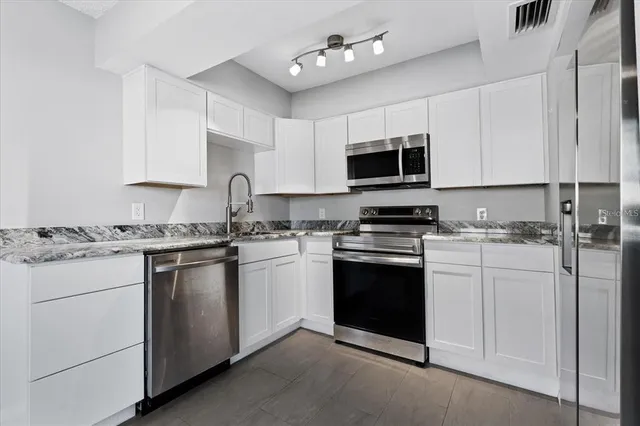 a kitchen with granite countertop white cabinets and stainless steel appliances