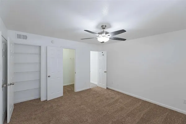 an empty room with a ceiling fan and a window
