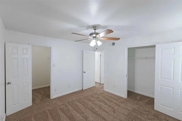 a view of an empty room with a chandelier fan