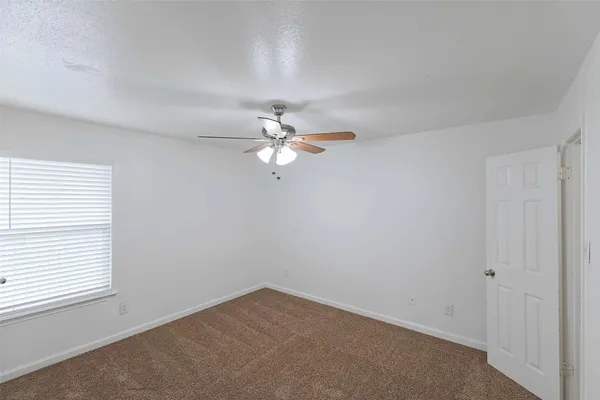 an empty room with a window and a fan
