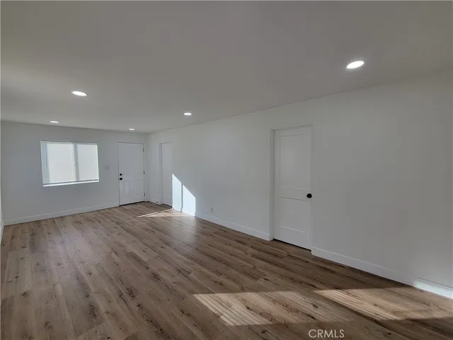 a view of an empty room with wooden floor and closet