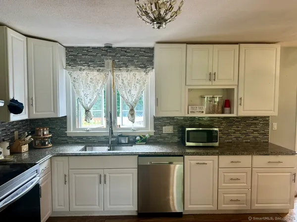 a kitchen with granite countertop a sink window and cabinets