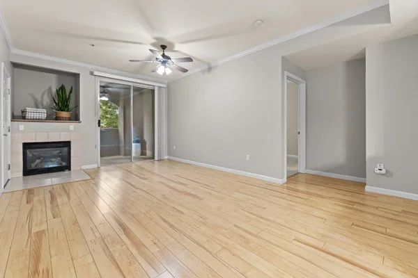 a view of an empty room with wooden floor fireplace and a window