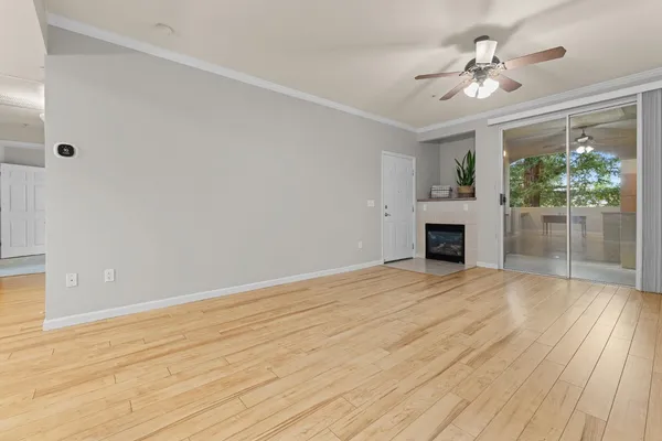 a view of empty room with wooden floor and fan
