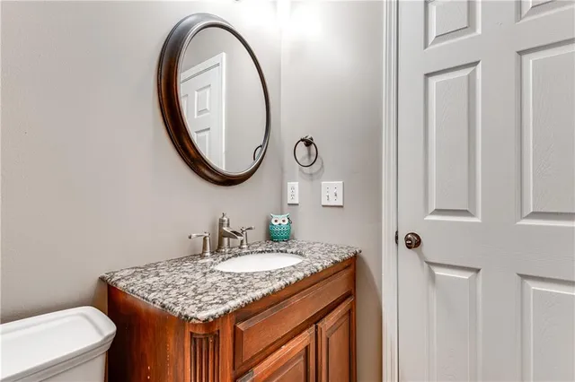 a bathroom with a granite countertop sink mirror vanity and a toilet