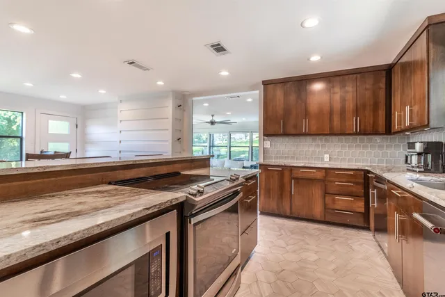 a kitchen with stainless steel appliances granite countertop wooden cabinets a stove a sink and a granite counter tops