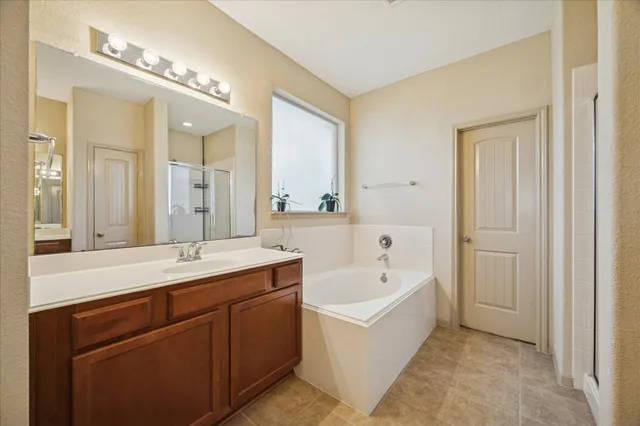 a spacious bathroom with a tub double sink and mirror