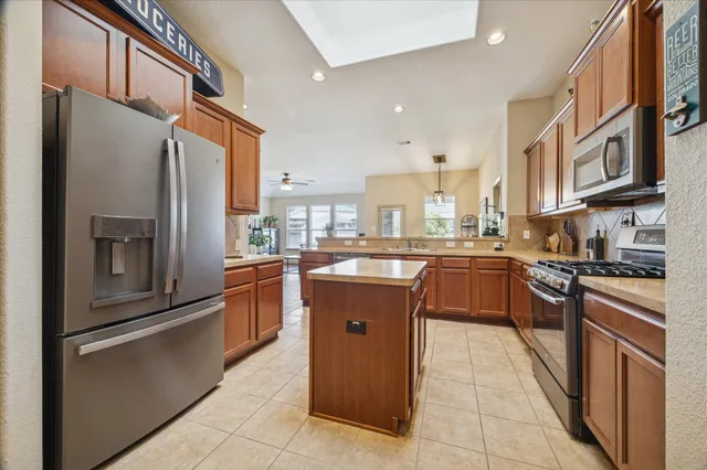 a kitchen with stainless steel appliances granite countertop a refrigerator a stove top oven and sink