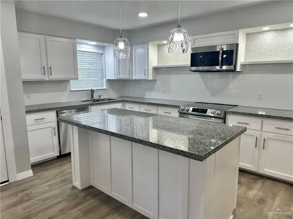 a kitchen with stainless steel appliances granite countertop a sink dishwasher a stove and a microwave oven with wooden floor