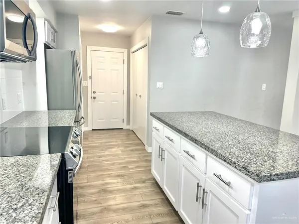 a view of a kitchen with granite countertop cabinets and chandelier