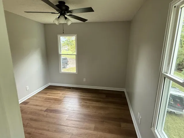 an empty room with windows and fan