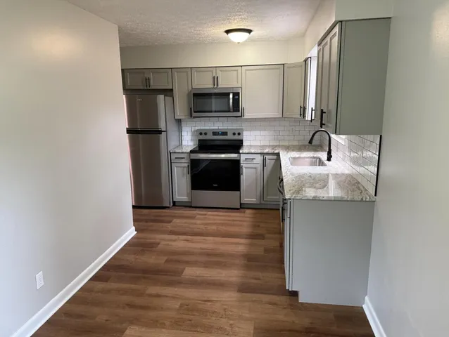 a kitchen with granite countertop a refrigerator and a stove top oven