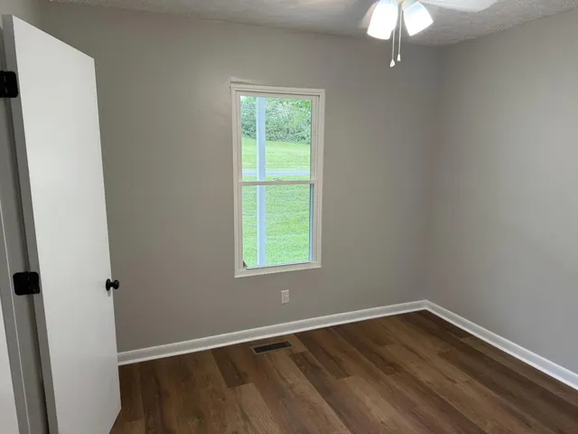 an empty room with wooden floor and windows