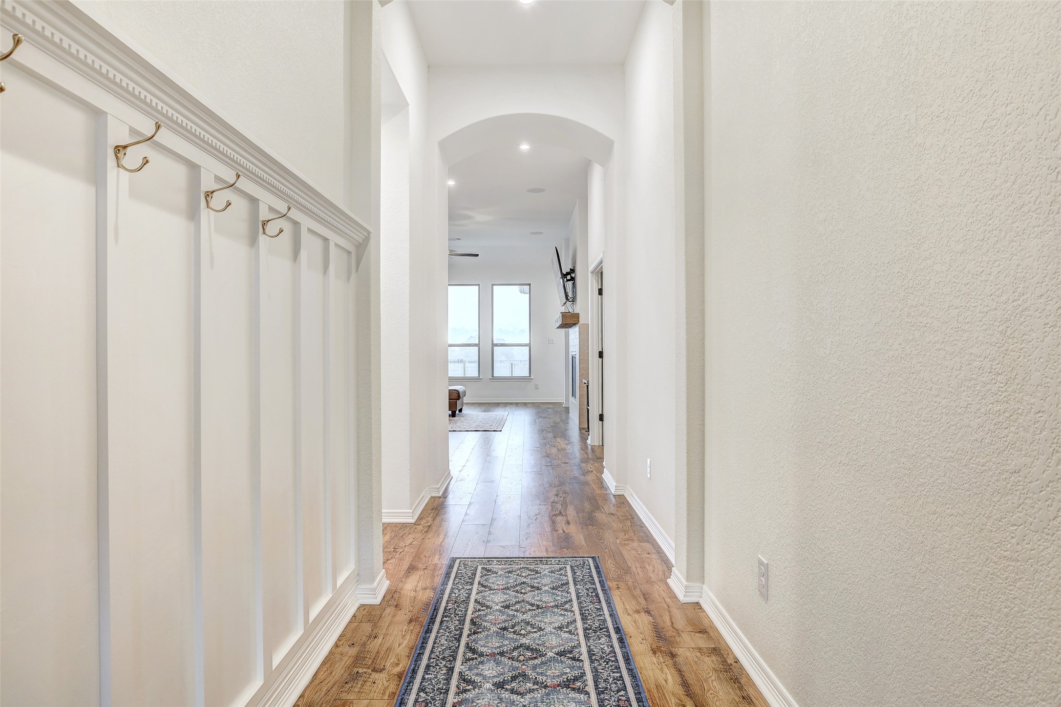 1117 Spring Gulch Lane Georgetown, TX 78628 - Photo 4 of 39 An inviting hallway with warm hardwood flooring and crisp white wainscoting leads to sun-filled living areas.