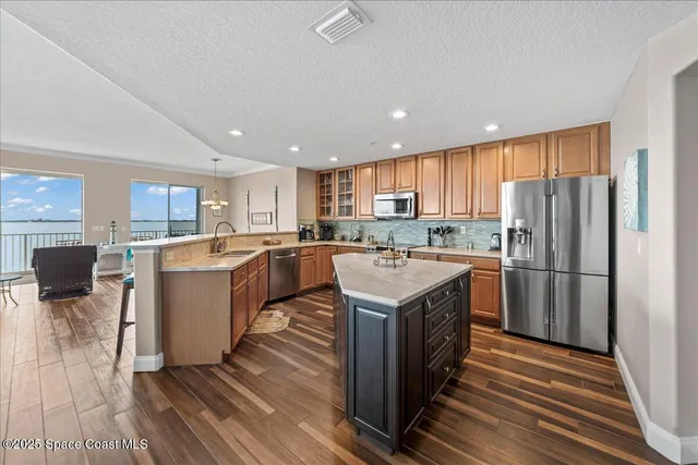 a living room with stainless steel appliances kitchen island granite countertop furniture and a large window