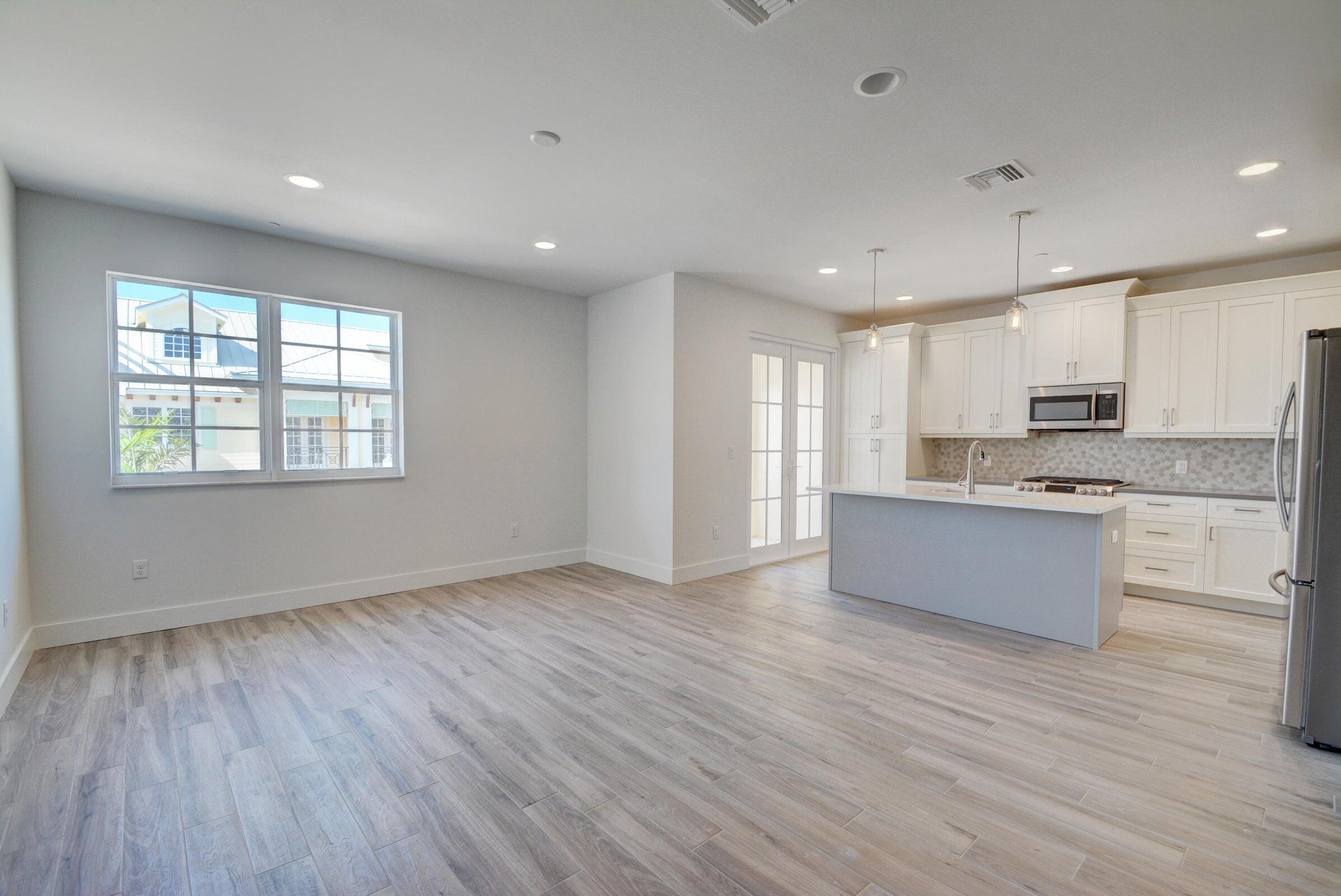 3770 County Line Road, Unit C2 Tequesta, FL 33469 - Photo 11 of 27 a large kitchen with stainless steel appliances granite countertop a stove a sink and white cabinets with wooden floor