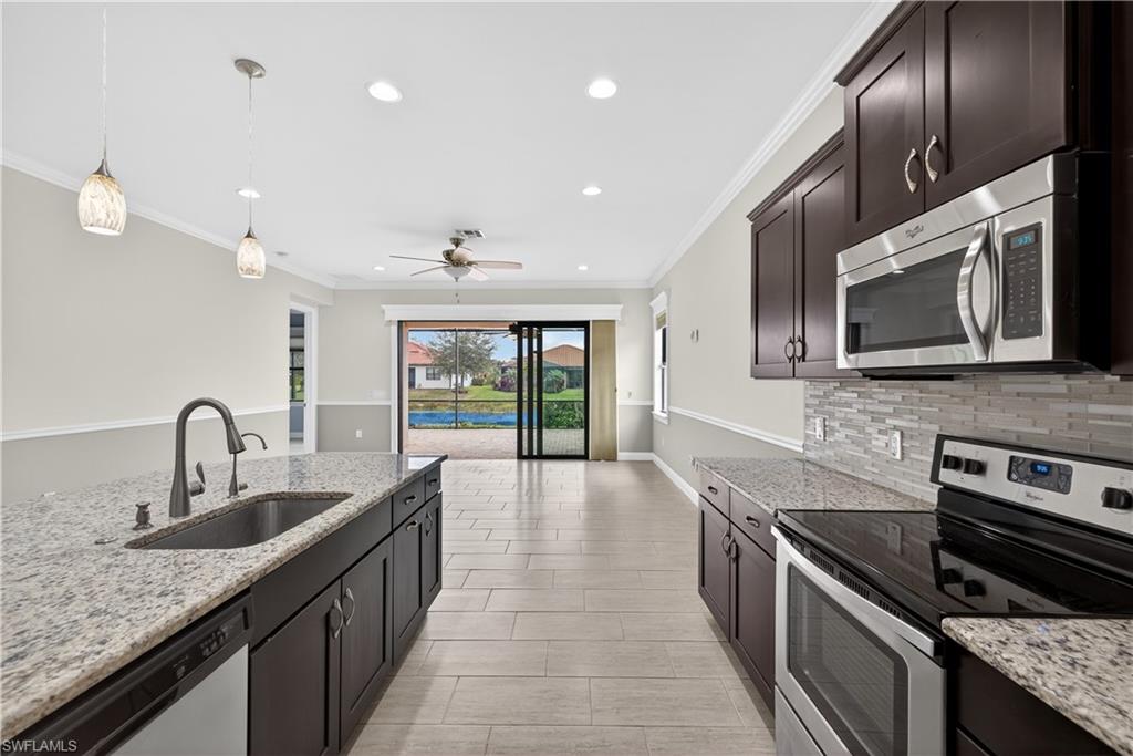 1412 Lucena Lane South Naples, FL 34113 - Photo 11 of 49 Kitchen with large island, pendant light fixtures, granite counters, tile backsplash, stainless steel appliances, pantry and tranquil water views.