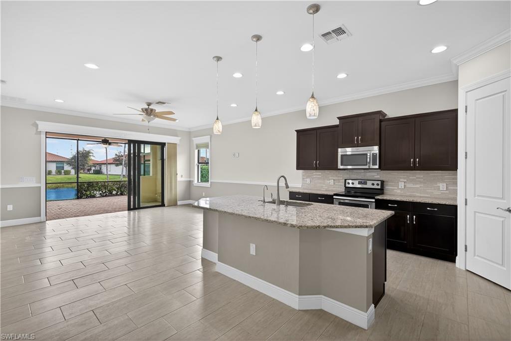 1412 Lucena Lane South Naples, FL 34113 - Photo 6 of 50 Kitchen with large island, pendant light fixtures, granite counters, tile backsplash, stainless steel appliances, pantry and tranquil water views.