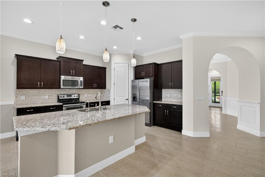 1412 Lucena Lane South Naples, FL 34113 - Photo 7 of 49 Kitchen with large island, pendant light fixtures, granite counters, tile backsplash, stainless steel appliances, and pantry.