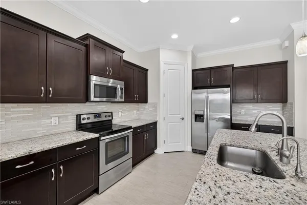 a kitchen with stainless steel appliances granite countertop a sink stove microwave and refrigerator