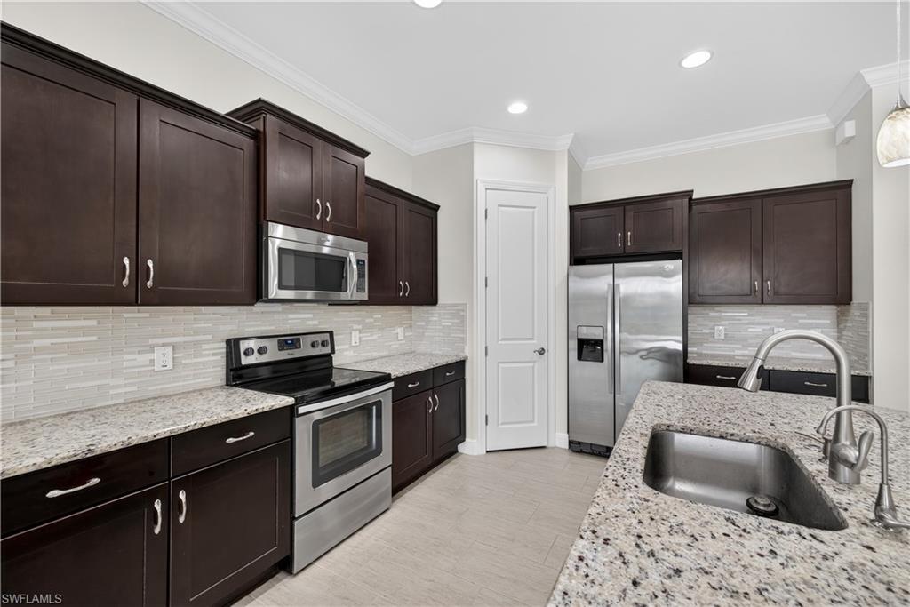 1412 Lucena Lane South Naples, FL 34113 - Photo 8 of 49 Kitchen with large island, pendant light fixtures, granite counters, tile backsplash, stainless steel appliances, and pantry.