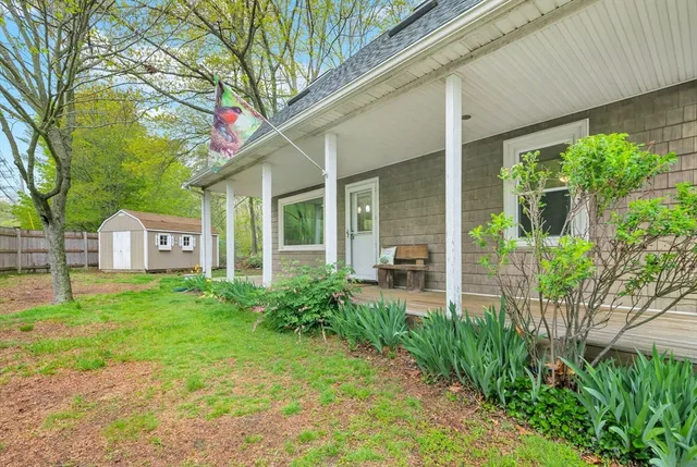 a view of a house with a small yard and a large tree