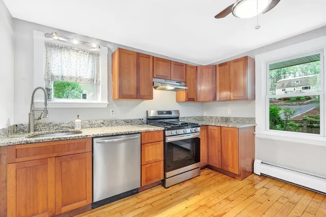 a kitchen with granite countertop wooden cabinets stainless steel appliances a sink and a window