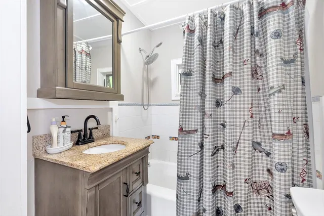 a bathroom with a granite countertop sink a mirror and shower