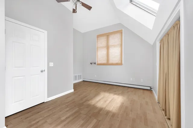 an empty room with wooden floor fan and windows