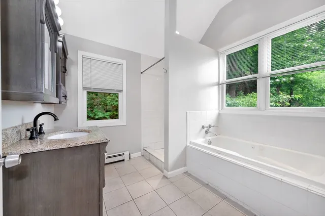 a bathroom with a granite countertop sink a bathtub and next to a window