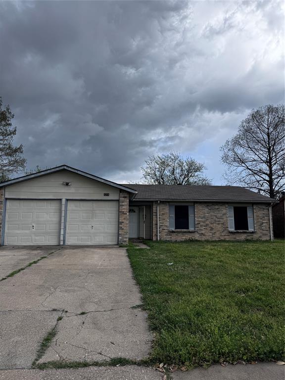 View of front of home featuring a garage, concrete driveway, and a front yard
