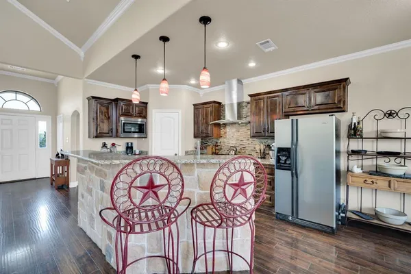 a kitchen with stainless steel appliances granite countertop a refrigerator a stove top oven a sink dishwasher a dining table and chairs with wooden floor