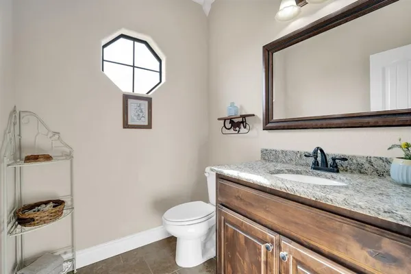 a bathroom with a granite countertop toilet sink mirror and vanity