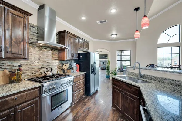 a kitchen with granite countertop stainless steel appliances a sink stove top oven and cabinets