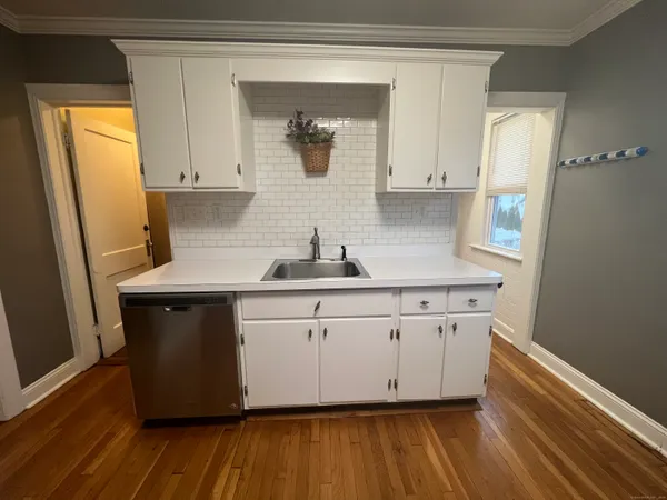 a kitchen with granite countertop white cabinets and wooden floor