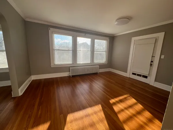 a view of empty room with wooden floor and floor to ceiling window