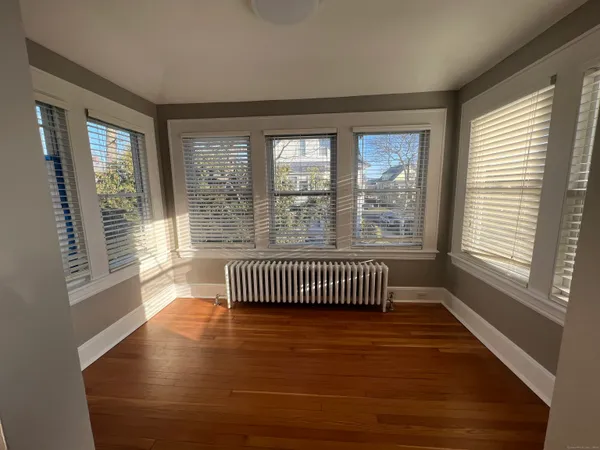 a view of an empty room with wooden floor and windows