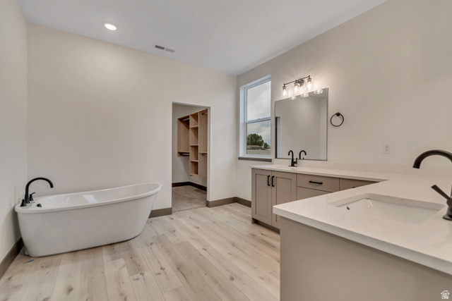 3317 South 1000 West, Unit 6010 Logan, UT 84321 - Photo 8 of 34 Full bathroom with double vanity, a freestanding bath, light wood-type flooring, a walk in closet, and recessed lighting