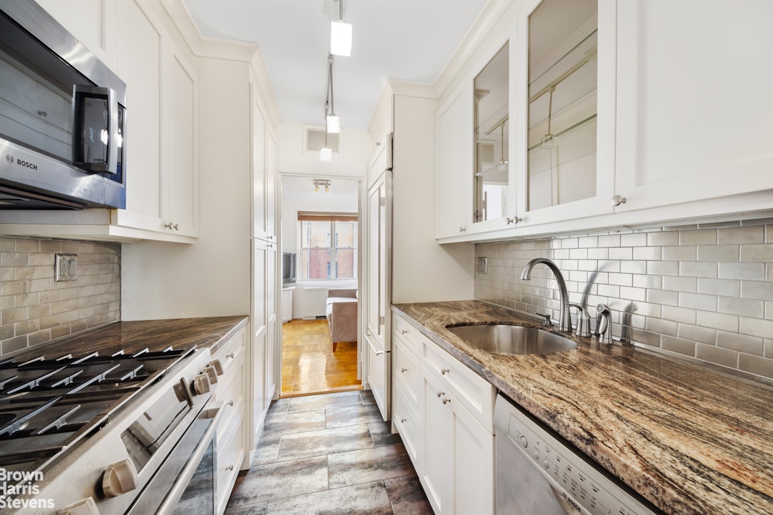150 East 61st Street, Unit 5F Manhattan, NY 10065 - Photo 4 of 15 a kitchen with stainless steel appliances granite countertop a sink stove and cabinets