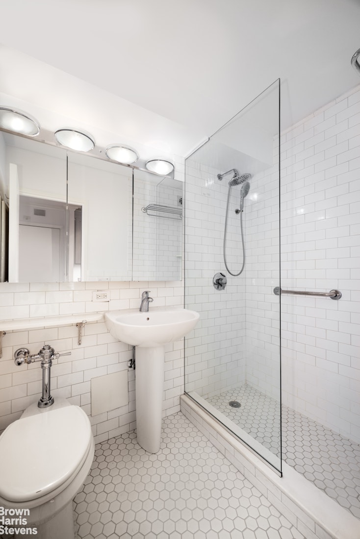 150 East 61st Street, Unit 5F Manhattan, NY 10065 - Photo 8 of 15 a bathroom with a sink a toilet and shower