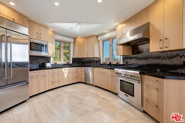 a large kitchen with stainless steel appliances granite countertop a stove a sink and a microwave